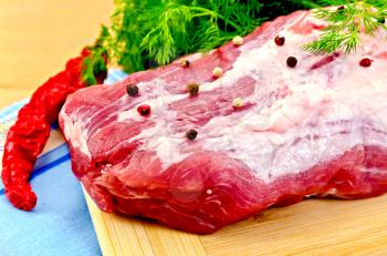 Large piece of meat with peas of different peppers, red pepper, parsley and dill, blue cloth on the background of wooden boards