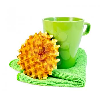 Round golden waffle, a green mug on the green napkin isolated on white background