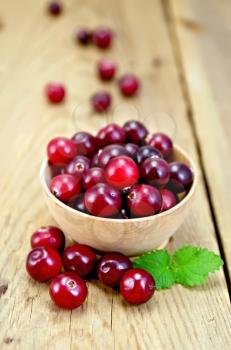 Cranberries in a wooden bowl, mint on the background of wooden boards