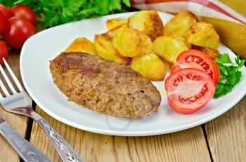 Cutlet meat with roasted potatoes, tomatoes and dill on a plate, parsley, napkin on wooden board