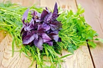 Beam of purple basil, parsley, tarragon and dill on a wooden boards background