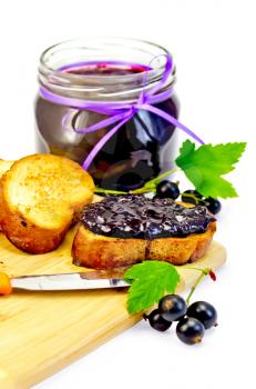 Slices of toasted bread, a glass jar with black currant jam, knife on the board isolated on white background