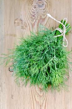 Bundle of dill, tied with twine on the background of wooden boards