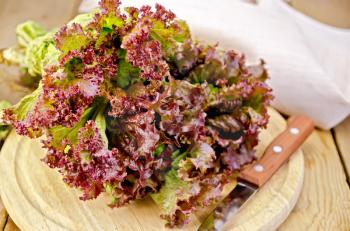 Red lettuce with a knife, napkin on the background of wooden boards