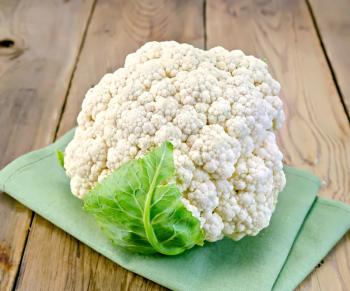 Cauliflower with green leaf on a napkin on the background of wooden boards