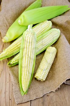 Corn on the cob on burlap on a wooden boards background