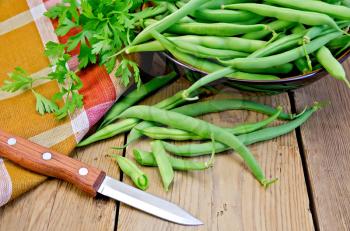 Beans asparagus green, checkered napkin, knife, parsley on a wooden boards background