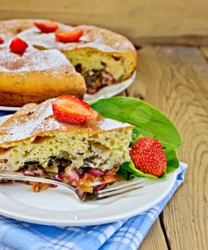 Piece of sweet cake with strawberries and sorrel, napkin, fork on the background of wooden boards