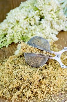 Metal sieve with dried flowers of meadowsweet, a bouquet of fresh flowers of meadowsweet on a wooden boards background