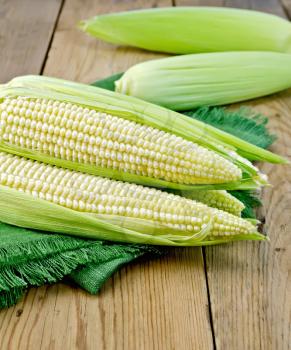 Purified corn cobs on a green napkin on a background of wooden boards