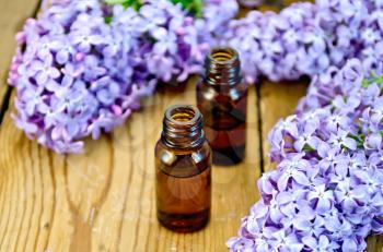 Oil in a bottle, lilac flowers on the background of wooden boards