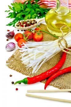 Rice noodles, tomatoes, various peppers, chopsticks, garlic, vegetable oil, burlap, cloth isolated on white background