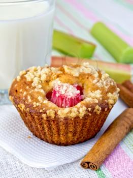 Cupcake with rhubarb, cinnamon on a paper napkin, rhubarb, milk in a glass on a background of a linen tablecloth