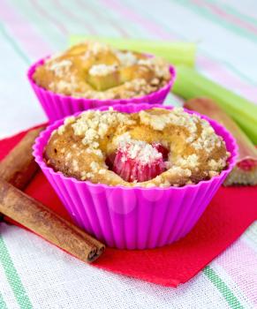 Cupcakes in tins with rhubarb, rhubarb, cinnamon on a red paper napkin on a linen tablecloth background