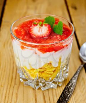Milk dessert with strawberries, corn flakes and yogurt, spoon on a background of wooden boards