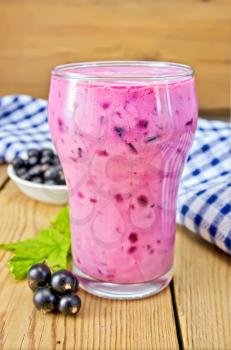 Milkshake with black currants in a glass, a napkin, currants against the background of wooden boards