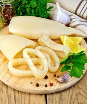 Whole and sliced squid rings, lemon, garlic, pepper, parsley, napkin nafone wooden board