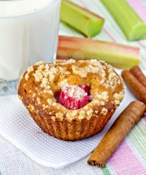 Cupcake with rhubarb, cinnamon on a paper napkin, rhubarb stalks, milk in a glass on a background of a linen tablecloth