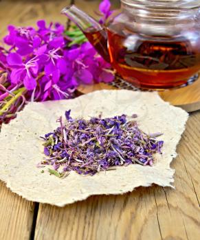 Fireweed dry on paper, teapot with tea, fresh flowers fireweed on a wooden boards background