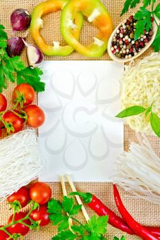 Sheet of white paper, frame made of rice noodles, tomatoes, peppers, parsley, basil and garlic on a sacking