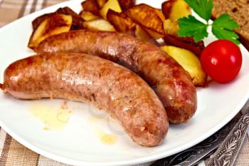 Pork sausages and potatoes fried in a dish, bread, tomato, parsley, fork, knife, against a linen tablecloth