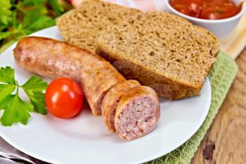Pork sausages grilled in the plate on a napkin, bread, sauce, tomato, parsley on a wooden boards background