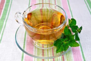 Herbal tea in a glass cup, fresh mint leaves on a background of a linen tablecloth