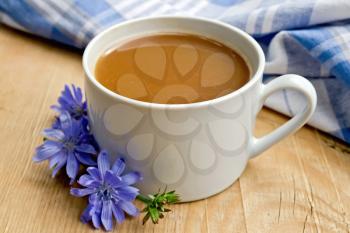 Chicory drink in a white cup with flower, napkin on a wooden boards background