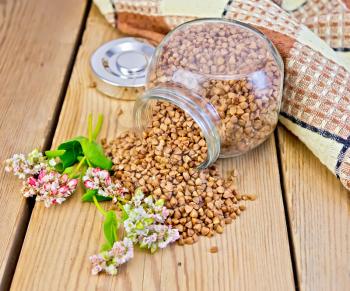 Buckwheat in a glass jar, flower buckwheat, napkin on the background of wooden boards