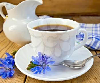 Chicory drink in a white cup with a flower on a saucer and spoon, napkin, milk jug on a wooden board
