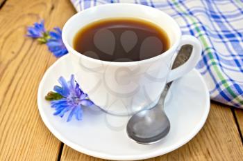 Chicory drink in a white cup with a flower on a saucer and spoon, napkin on wooden board