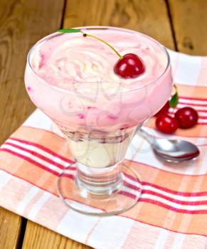 Dessert dairy with cherries and cream curd, spoon on a napkin with cherries on a wooden boards background