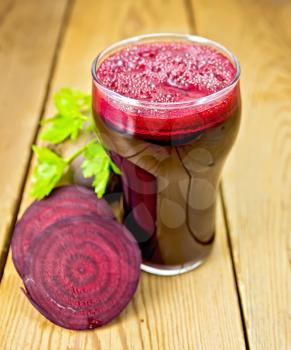 Beet juice in a glass, beets, parsley on a wooden boards background