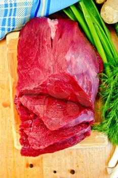 A piece of beef, peas pepper, dill, green onions, ginger root, blue cloth on a wooden board