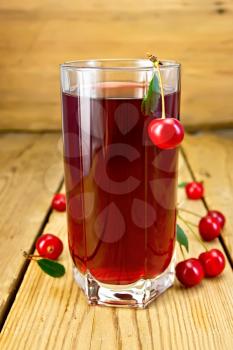 Cherry compote in a tall glass, cherries on a wooden boards background