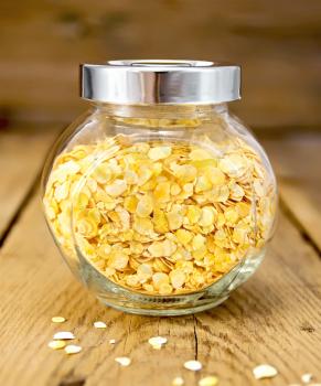Pea flakes in a glass jar on a wooden boards background