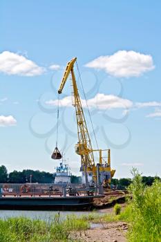 Loading sand with the help of a yellow crane on a barge. River White, Russia