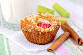 Cupcake with rhubarb, cinnamon on a white paper napkin, rhubarb, milk in a glass on a background of a linen tablecloth