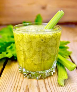 One glassful with a cocktail of celery stalks and leaves of celery on a wooden boards background