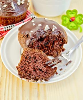 Chocolate cupcake, break a fork on a white plate, cup of tea on a wooden boards background