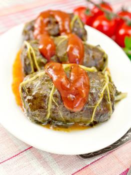Cabbage rolls with minced meat in the leaves of rhubarb in a plate with tomato sauce, tomatoes on linen background