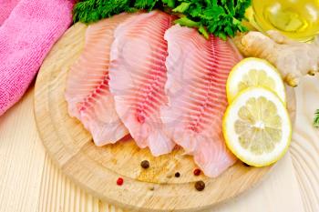 Tilapia fillets, dill, parsley, lemon, ginger, cloth, vegetable oil on a wooden boards background