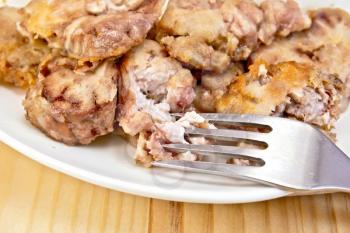 Plate with fried brains and fork on a wooden boards background