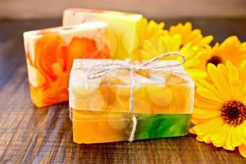 Homemade soap, yellow marigold on a wooden boards background