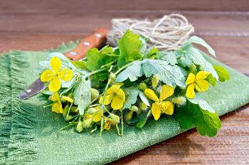 A bunch of flowers celandine, tied with twine, a knife on a green napkin on a background of wooden planks