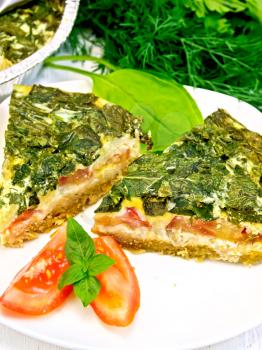 Two pieces of cake Celtic with spinach, tomatoes, oatmeal and eggs in a white plate, parsley, dill on a wooden boards background