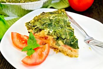 Celtic cake with spinach, tomatoes, oatmeal and eggs in a white plate in a baking dish from a foil, a napkin, parsley on a wooden board