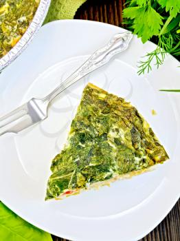 Celtic cake with spinach, tomatoes, oatmeal and eggs in a white plate on the background of wooden boards on top