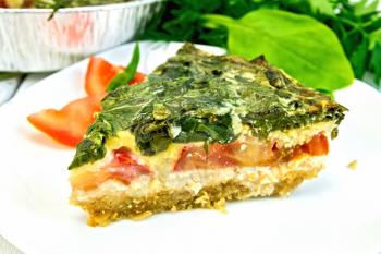 Celtic cake with spinach, tomatoes, oatmeal and eggs in a white plate in a baking dish from a foil on a wooden boards background