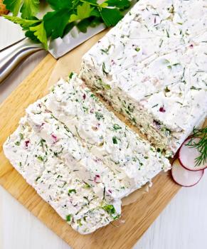 Terrine of curd and radish with dill, green onions on a paper and a board, knife, parsley on a light wooden planks on top